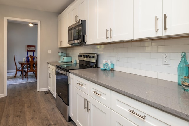 kitchen featuring dark wood-type flooring, white cabinetry, tasteful backsplash, appliances with stainless steel finishes, and light stone countertops