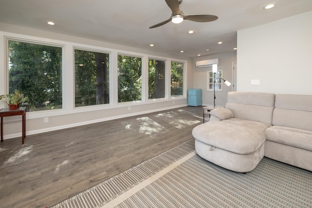 living room featuring wood-type flooring, ceiling fan, and a wall unit AC