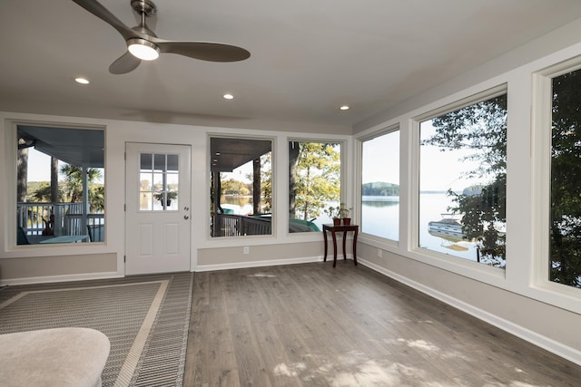 unfurnished sunroom with a water view and ceiling fan