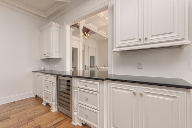 kitchen featuring white cabinets, beverage cooler, a chandelier, ornamental molding, and light hardwood / wood-style flooring