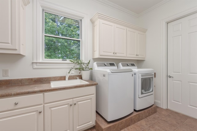 clothes washing area featuring sink, cabinets, ornamental molding, light tile patterned floors, and washer and clothes dryer