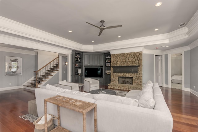 living room featuring dark hardwood / wood-style flooring, a fireplace, ornamental molding, and ceiling fan