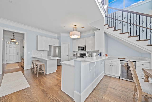 112-UNIT309 Indian Summer Path, Eatonton, GA 31024 - kitchen with stainless steel appliances, a peninsula, beverage cooler, crown molding, and white cabinetry