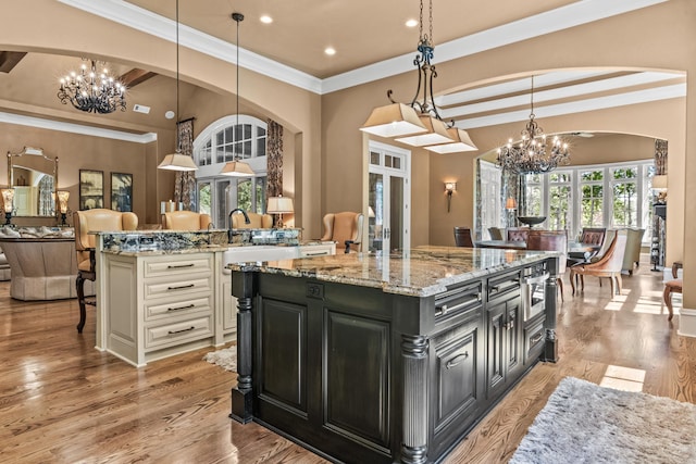 1031 Sugar Run, Greensboro, GA 30642 - kitchen featuring a chandelier, dark cabinets, open floor plan, a kitchen bar, and crown molding