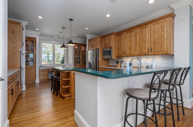 kitchen with a sink, stainless steel appliances, open shelves, and light wood-style flooring