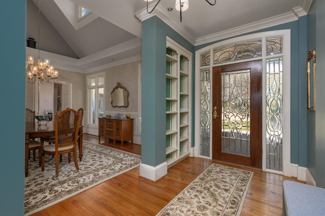 entrance foyer with a chandelier, a healthy amount of sunlight, wood finished floors, and crown molding