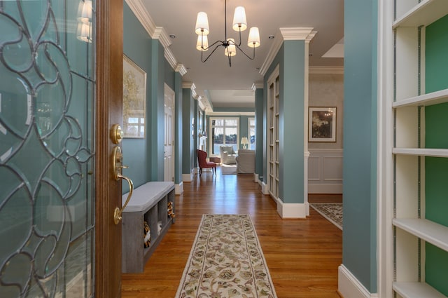 foyer with a notable chandelier, crown molding, baseboards, and wood finished floors