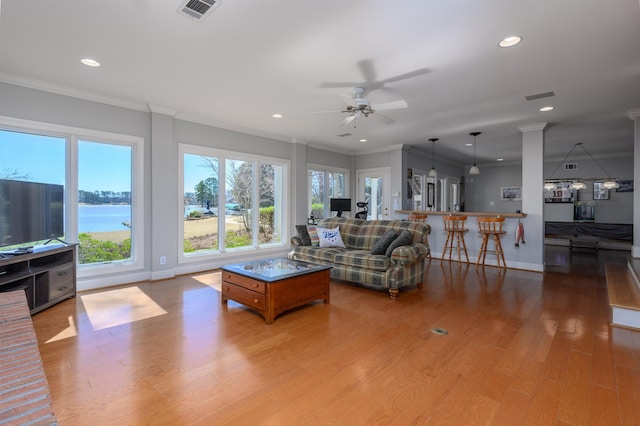 living room with recessed lighting, visible vents, light wood finished floors, and ornamental molding