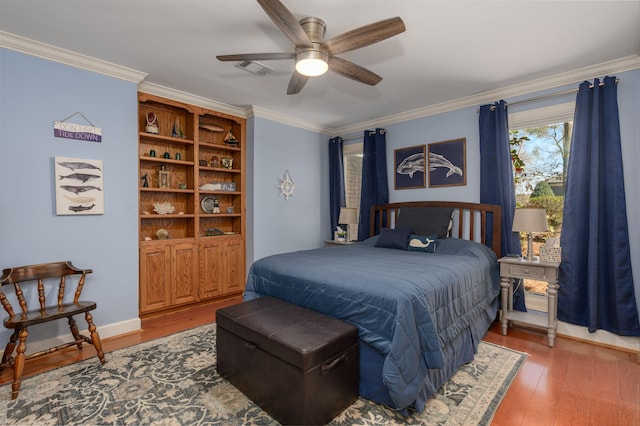 bedroom with visible vents, crown molding, baseboards, ceiling fan, and wood finished floors