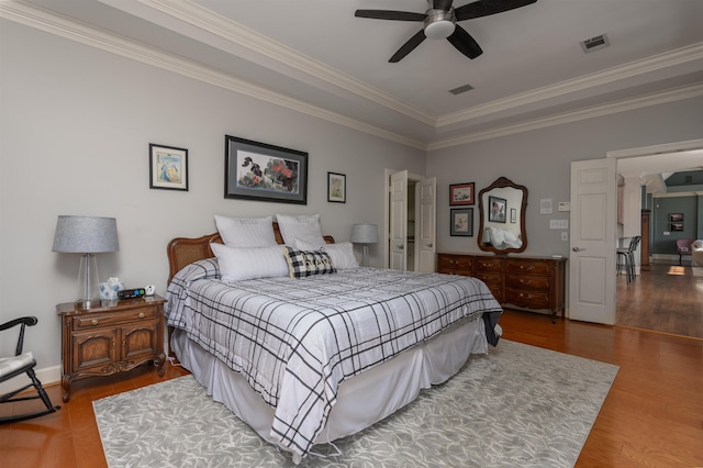 bedroom with visible vents, crown molding, and wood finished floors