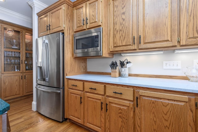 140 Winnstead Pl, Eatonton, GA 31024 - kitchen featuring stainless steel appliances, crown molding, light countertops, light wood-style floors, and brown cabinetry