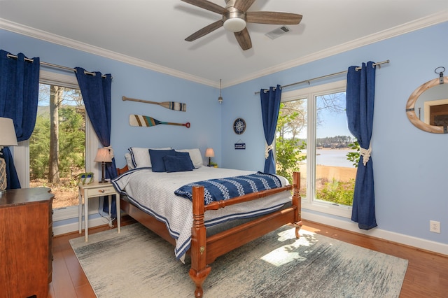 bedroom featuring visible vents, crown molding, baseboards, and wood finished floors