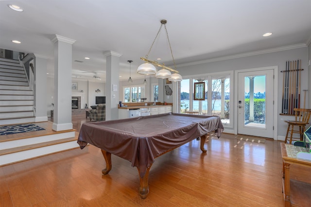 playroom with a brick fireplace, a healthy amount of sunlight, light wood finished floors, and ornamental molding