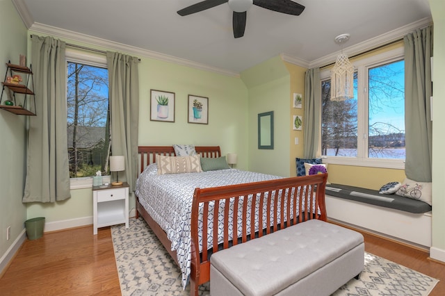 bedroom featuring a ceiling fan, crown molding, baseboards, and wood finished floors