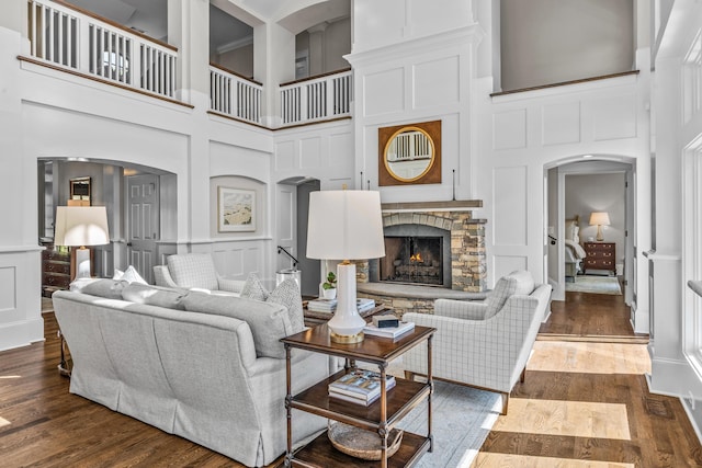 1140 Plantation Point Dr, Greensboro, GA 30642 - living room featuring a high ceiling, a fireplace, a decorative wall, arched walkways, and dark wood-type flooring