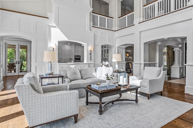 1140 Plantation Point Dr, Greensboro, GA 30642 - living room with a towering ceiling, a decorative wall, wood finished floors, ornate columns, and arched walkways