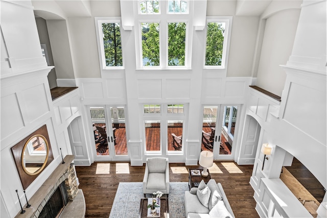 1140 Plantation Point Dr, Greensboro, GA 30642 - living room featuring french doors, a stone fireplace, a wainscoted wall, dark wood-style floors, and a decorative wall