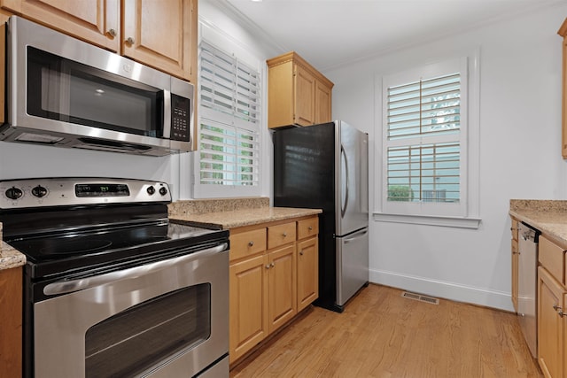 kitchen featuring appliances with stainless steel finishes, light brown cabinetry, light stone counters, crown molding, and light wood-type flooring