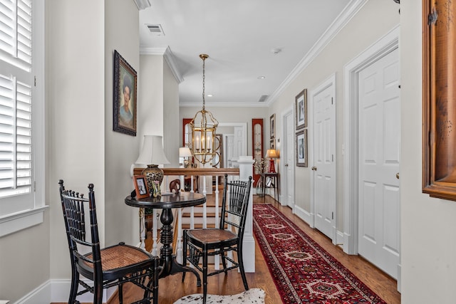 interior space featuring a chandelier, wood finished floors, visible vents, baseboards, and ornamental molding