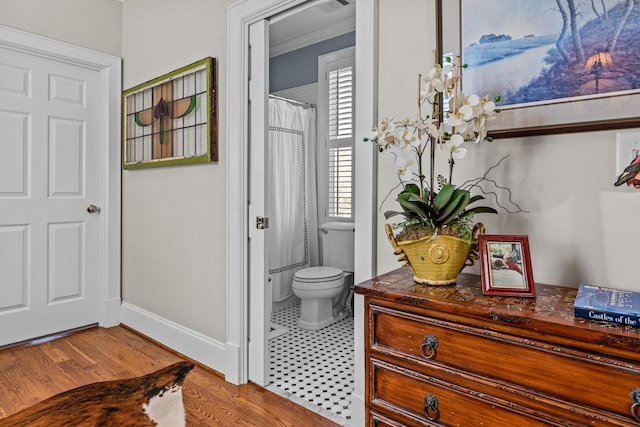 bathroom featuring toilet, baseboards, and wood finished floors