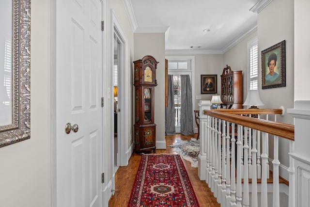 hallway with an upstairs landing, baseboards, crown molding, and wood finished floors