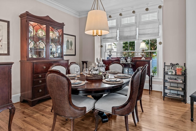 dining area with baseboards, ornamental molding, and wood finished floors