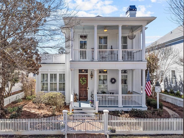 neoclassical / greek revival house featuring a fenced front yard, a chimney, a porch, a gate, and a balcony