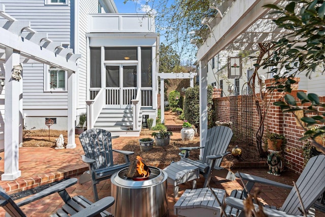 view of patio / terrace featuring an outdoor fire pit and a sunroom