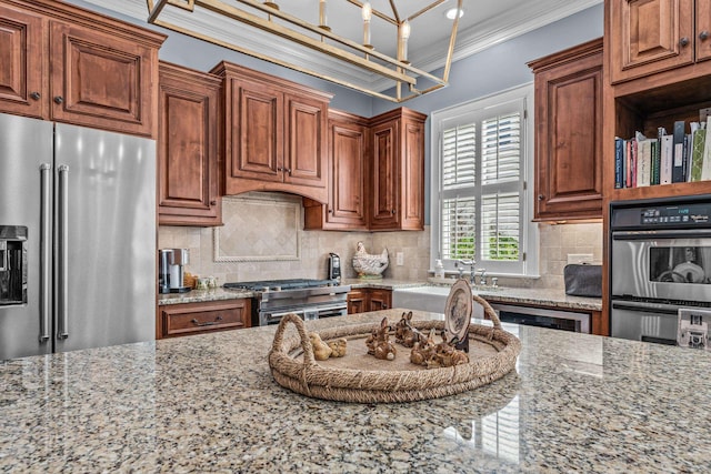 kitchen featuring tasteful backsplash, high end appliances, light stone counters, brown cabinets, and crown molding