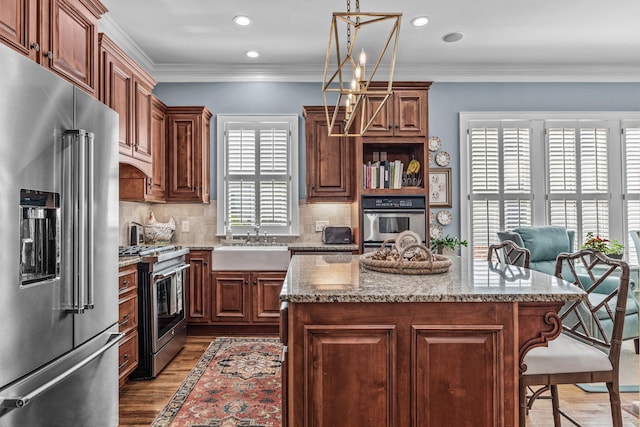 kitchen featuring a breakfast bar, stainless steel appliances, crown molding, light wood-style floors, and a sink