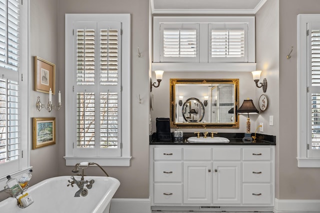 bathroom featuring plenty of natural light, a freestanding bath, vanity, and baseboards