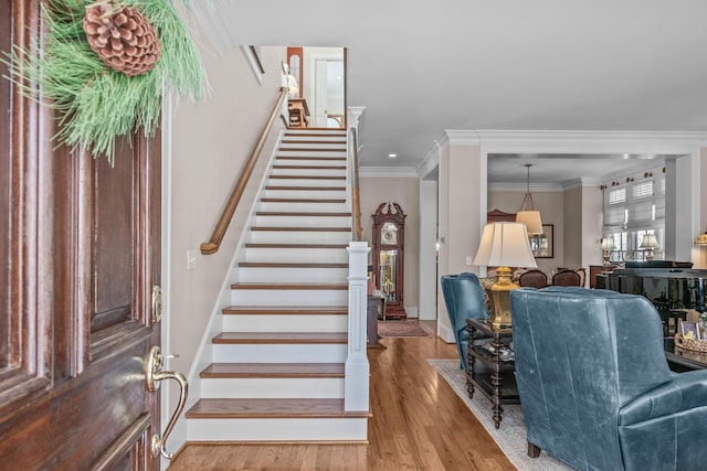 foyer entrance featuring ornamental molding, stairway, and wood finished floors