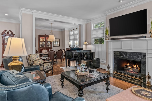 living area with ornamental molding, a fireplace, and wood finished floors