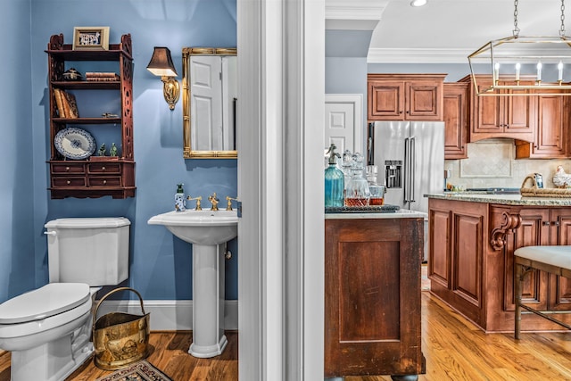 bathroom with ornamental molding, backsplash, wood finished floors, and toilet