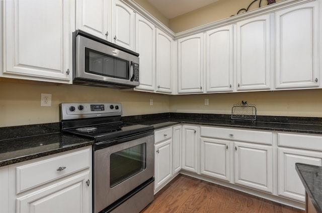 kitchen featuring white cabinetry, stainless steel appliances, dark wood-type flooring, and dark stone counters