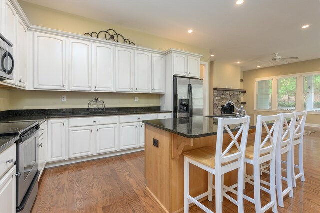 kitchen featuring sink, stainless steel appliances, a center island, white cabinets, and dark stone counters