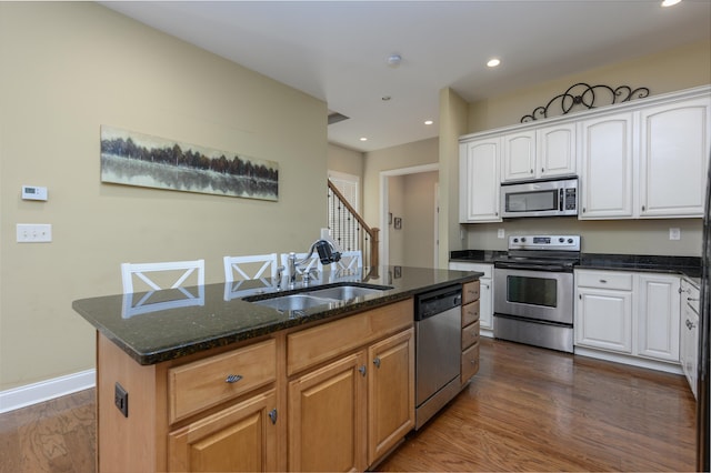 kitchen featuring stainless steel appliances, sink, a center island with sink, and white cabinets