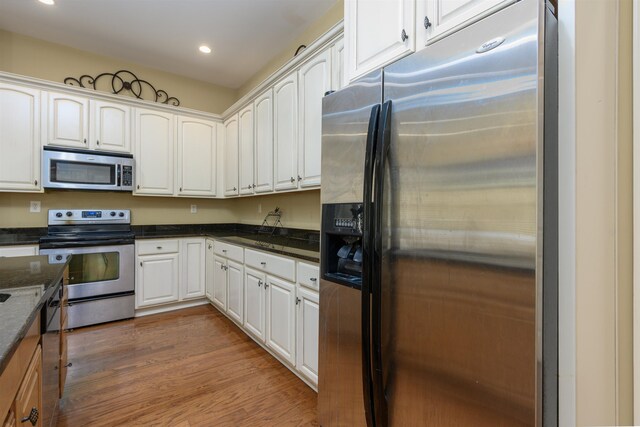 kitchen with white cabinetry, dark hardwood / wood-style flooring, stainless steel appliances, and dark stone countertops