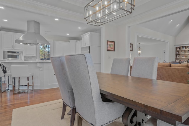 dining area with crown molding, a chandelier, and light wood-type flooring