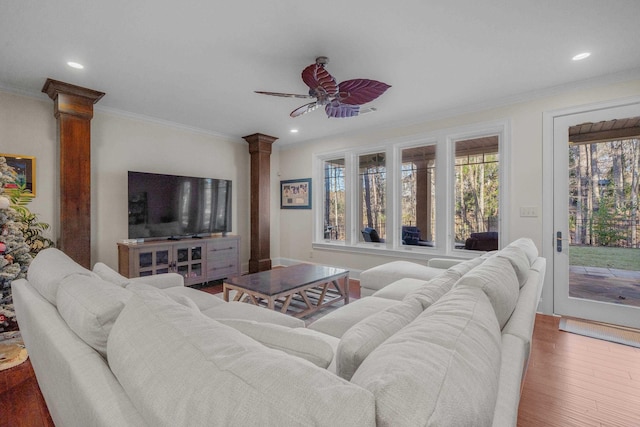 living room featuring hardwood / wood-style floors, crown molding, ceiling fan, and ornate columns