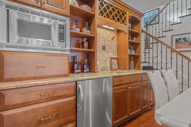 bar with stainless steel appliances, sink, light stone counters, and dark hardwood / wood-style floors