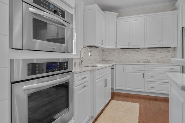 kitchen with white cabinetry, stainless steel oven, crown molding, and sink