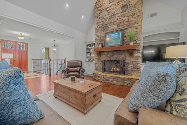 living room with high vaulted ceiling, a fireplace, and light hardwood / wood-style floors