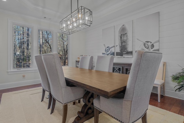 dining room with ornamental molding, a raised ceiling, and hardwood / wood-style floors