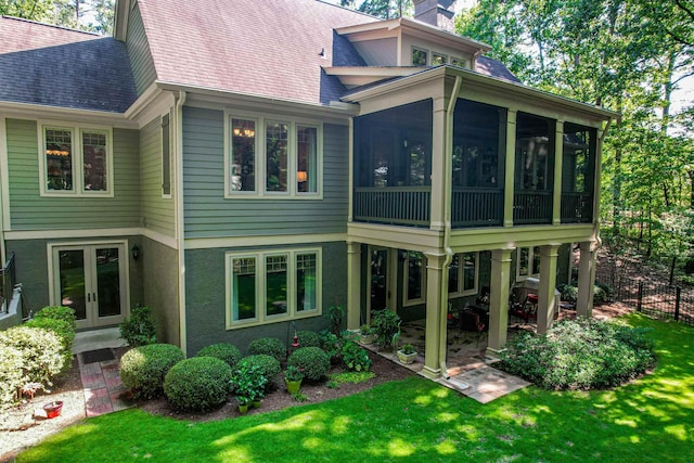 rear view of house featuring french doors, a yard, and a sunroom