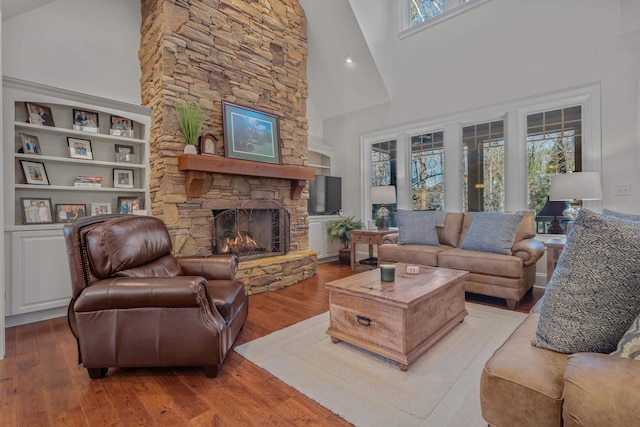 living room with wood-type flooring, a fireplace, and high vaulted ceiling