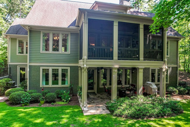 rear view of property featuring a patio, a sunroom, and a lawn