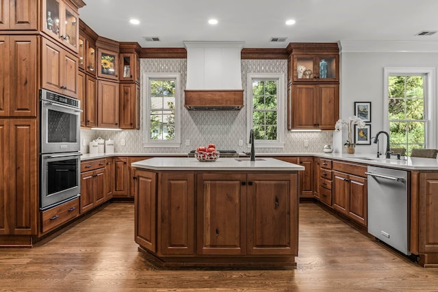 kitchen featuring sink, ornamental molding, kitchen peninsula, an island with sink, and stainless steel appliances