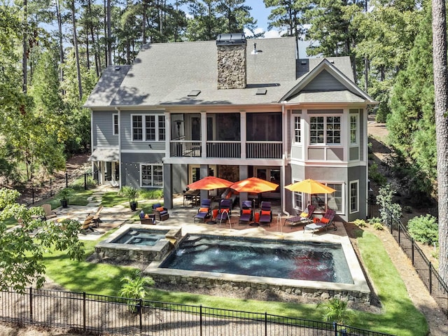 back of property featuring a pool with hot tub, a patio area, and a sunroom