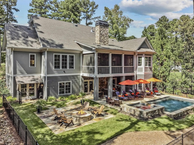 back of house with a swimming pool with hot tub, an outdoor fire pit, a patio area, and a sunroom